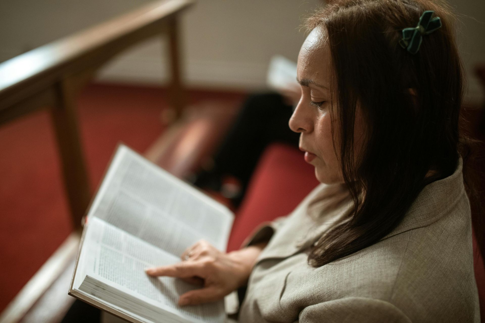 A woman in a church pew reading a Bible, showing devotion and faith.